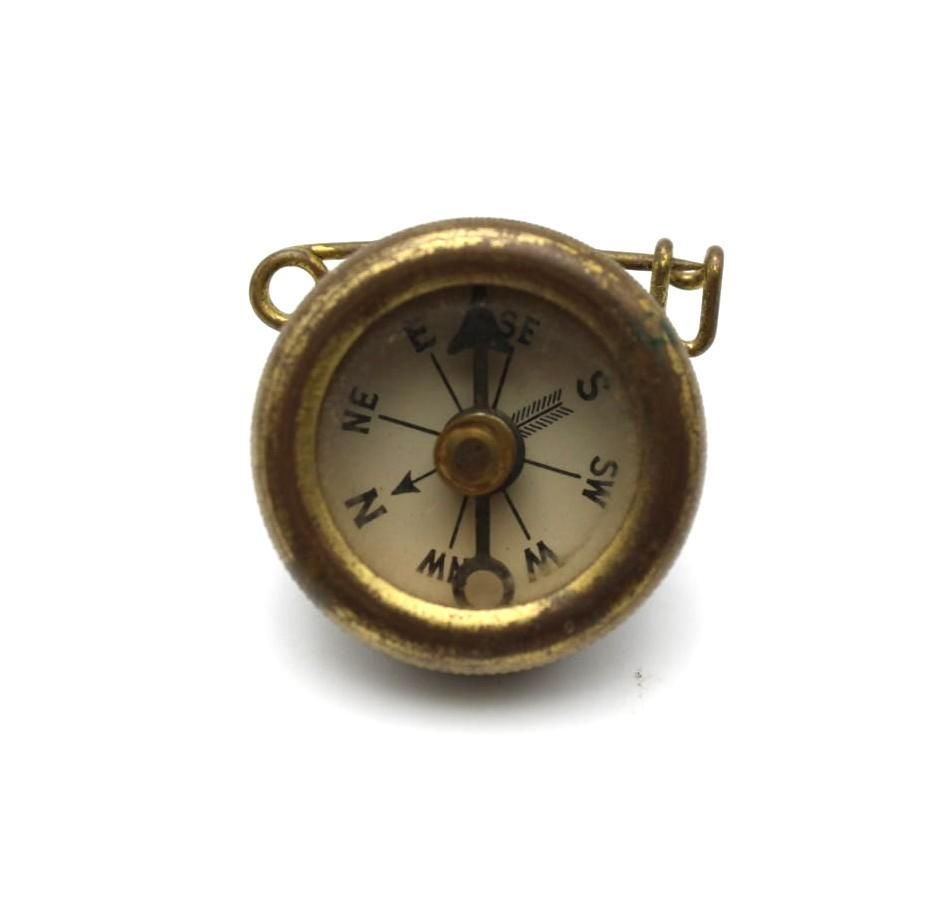 Small brass compass with a white face and black directional markings on a white background