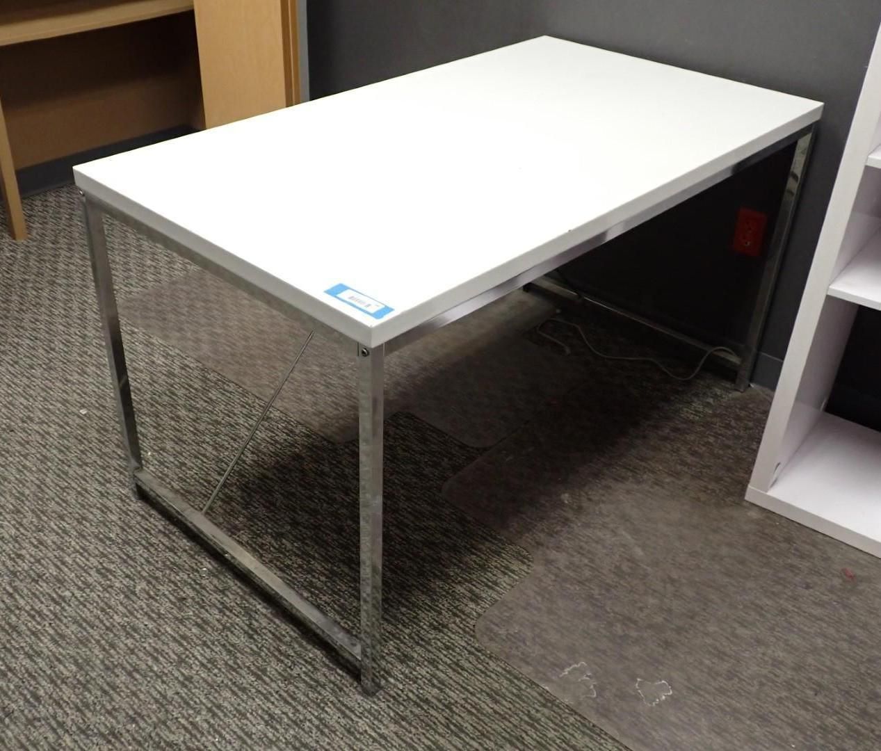 White office desk with chrome legs on carpet.