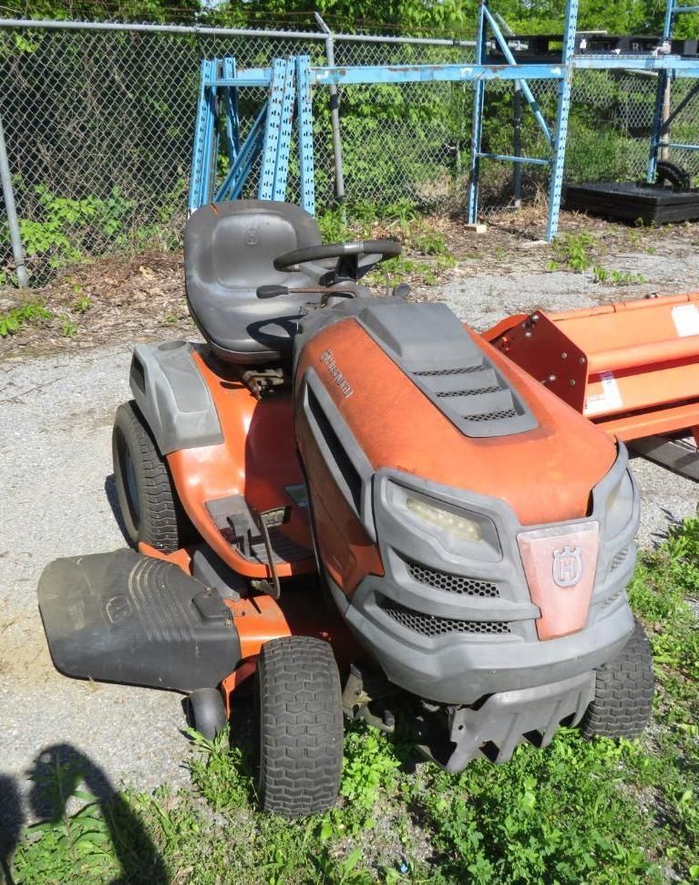 Orange and gray Husqvarna riding lawn mower on grass.