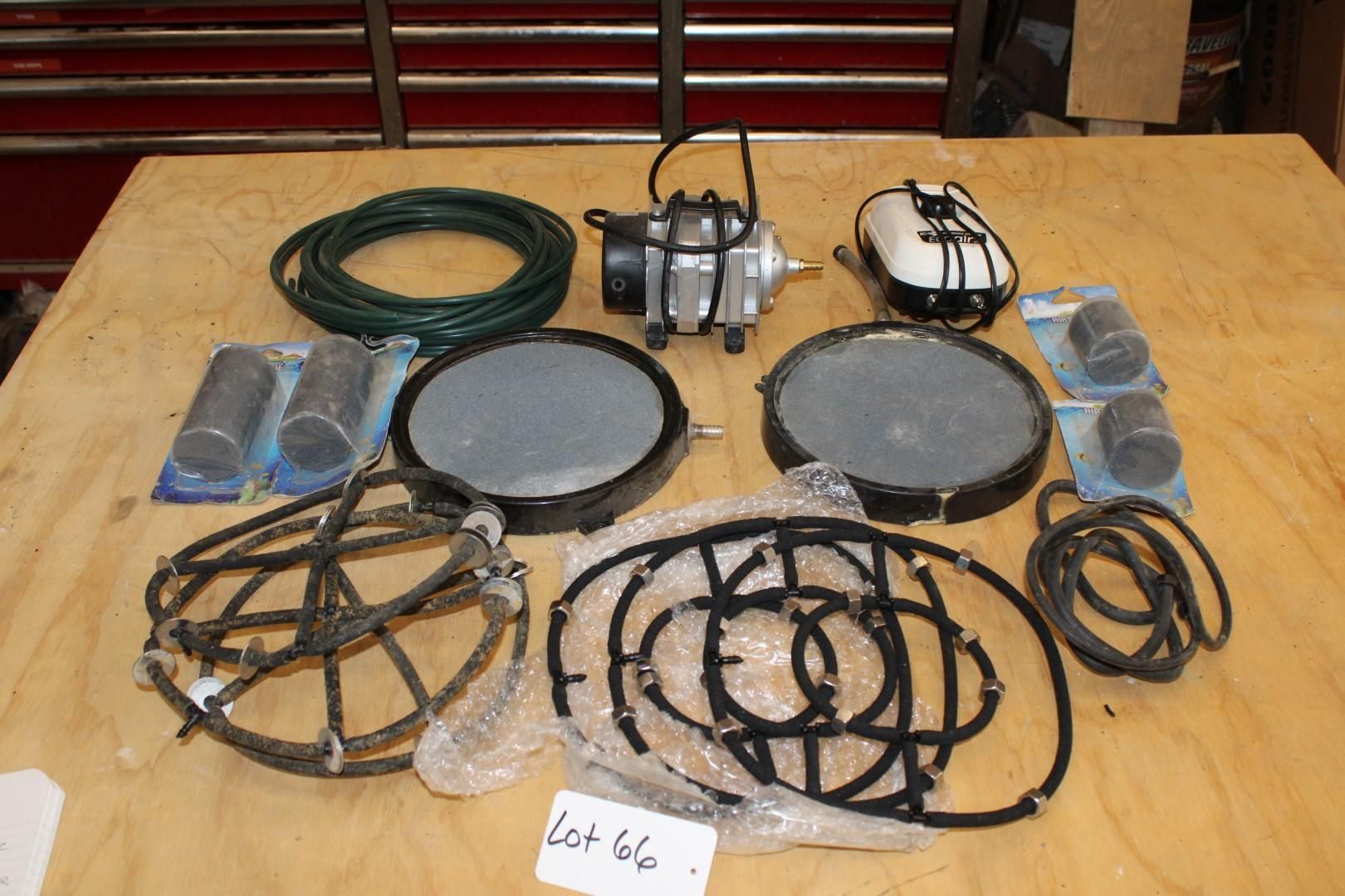 Various pond aeration equipment on a wooden surface, including pumps, diffusers, tubing, and air stones.