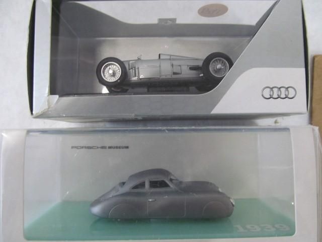 Two model cars in display cases: an Audi race car above a Porsche streamliner.