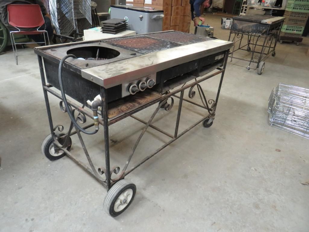 Black metal grill on wheels with cooking surface and side burner.