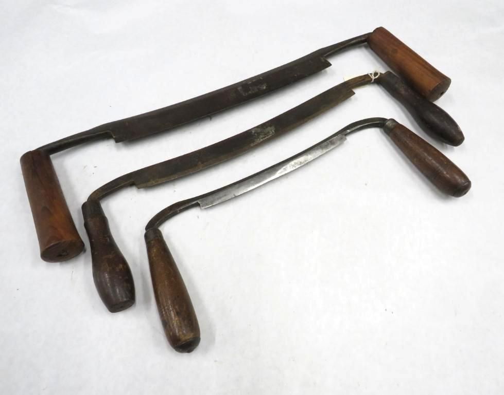 Three draw knives with wooden handles on a white surface.