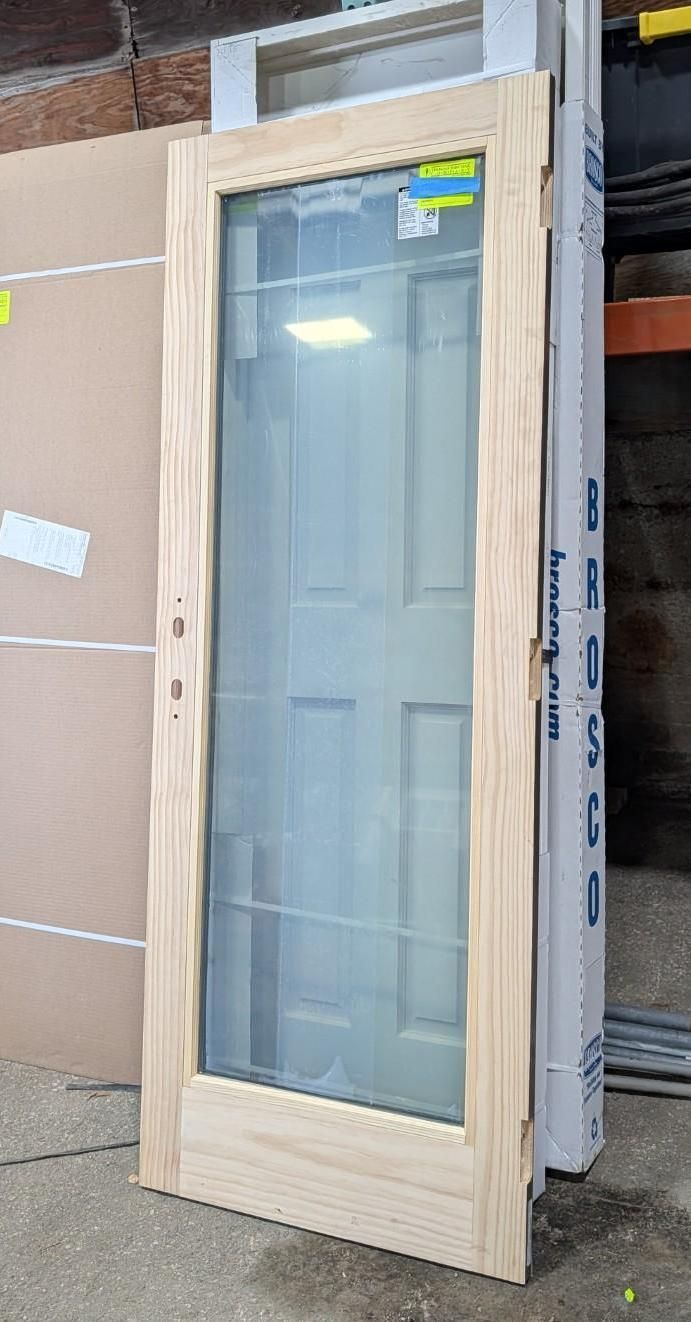 Wood-framed glass door leaning against stacked boxes in a storage area