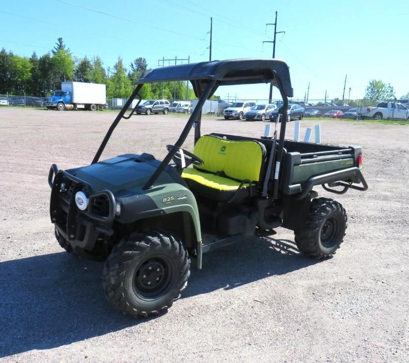 Green utility vehicle with black roll cage, on a paved lot.