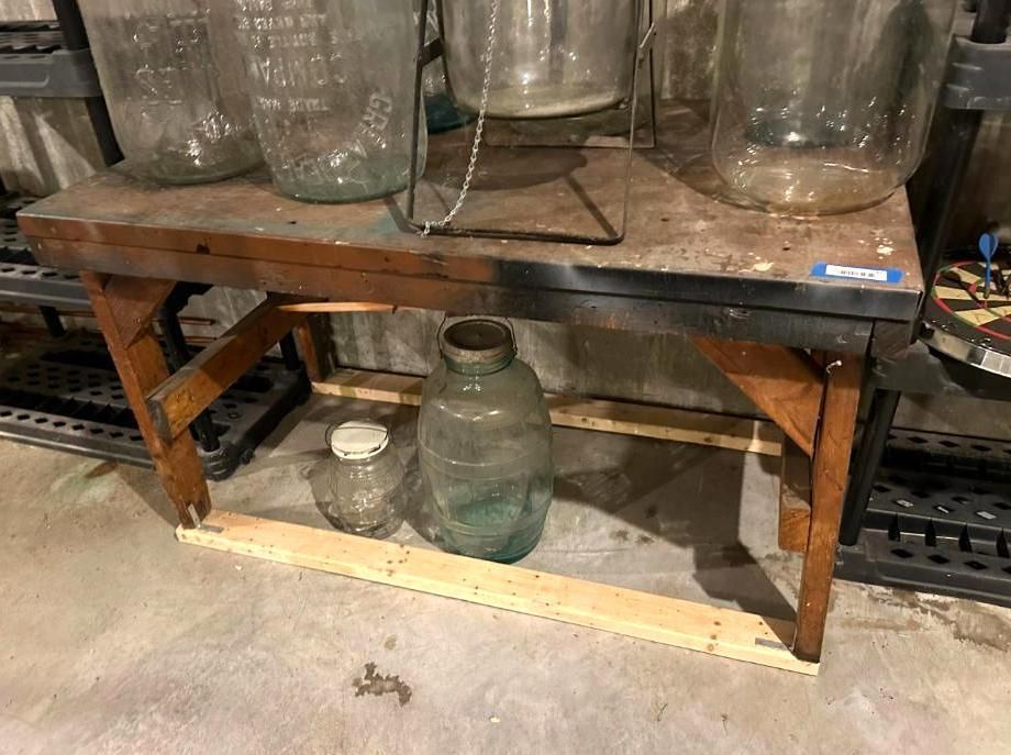 Wooden workbench holding glass jars. A smaller jar sits below the table.