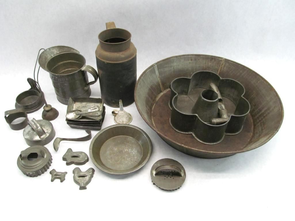 Collection of vintage tin kitchenware: baking pans, milk jug, cookie cutters, and other utensils.