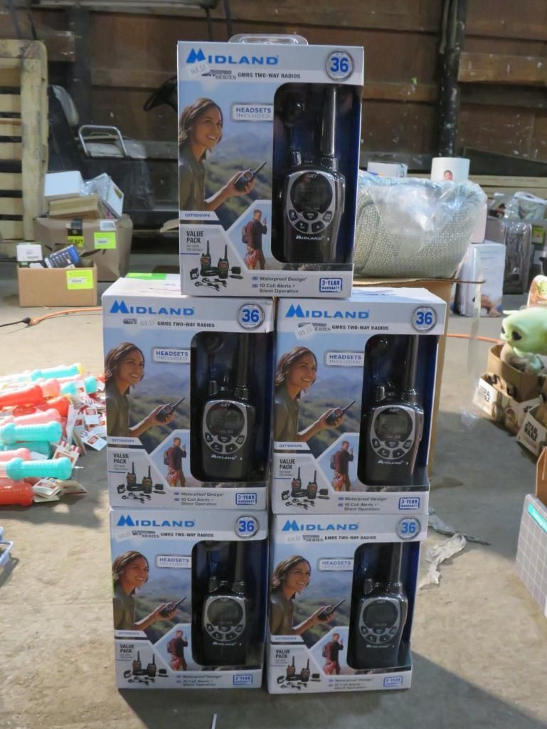 Six Midland walkie-talkie boxes stacked on a floor in a warehouse.