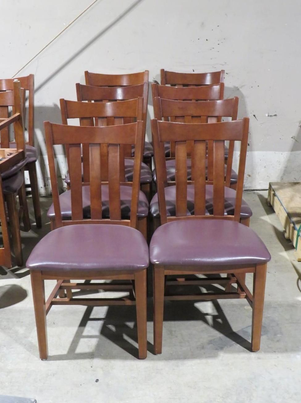 Group of wooden chairs with purple cushioned seats.