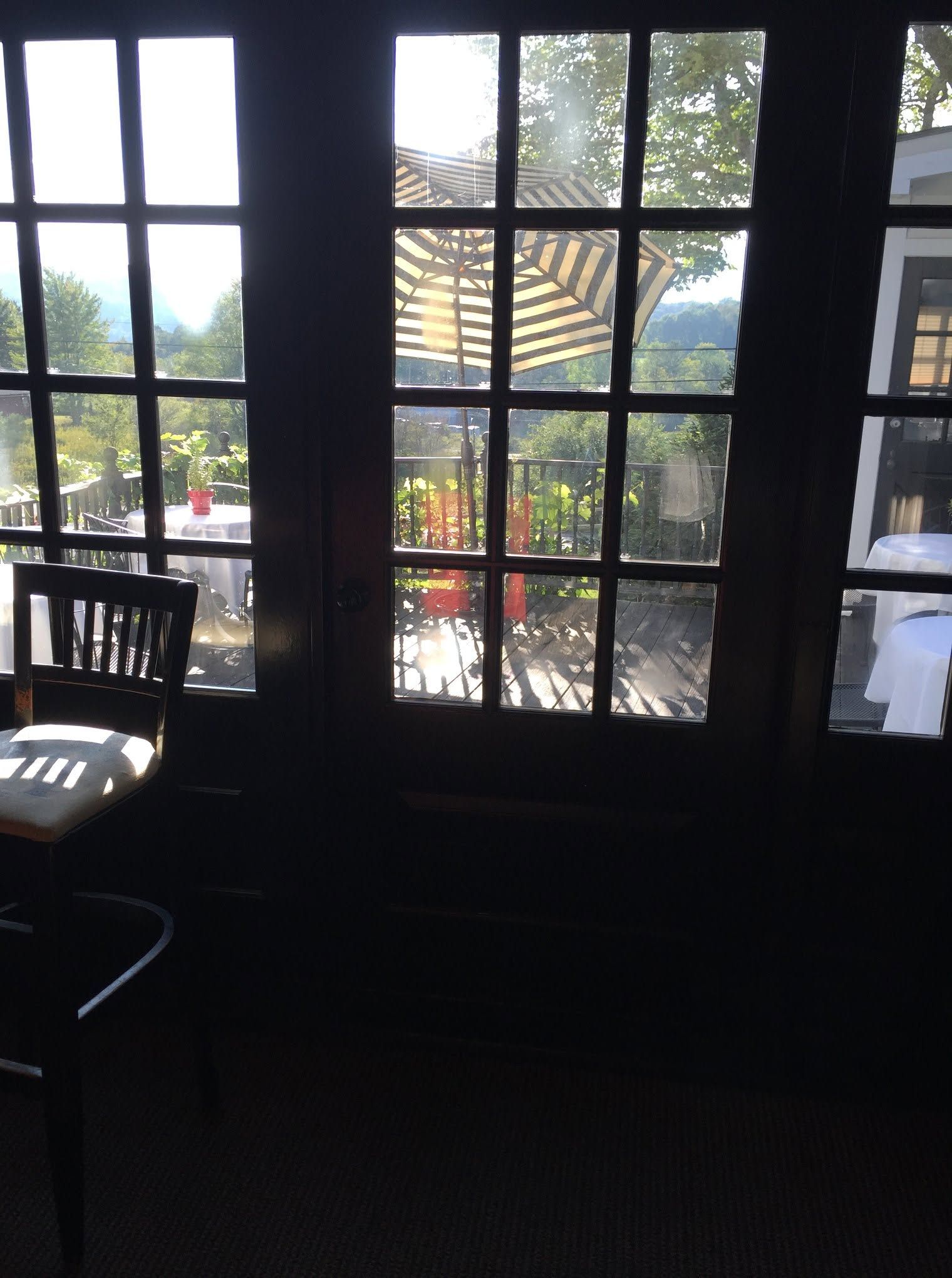 Dim room with a windowed glass door overlooking an outdoor patio and umbrellas