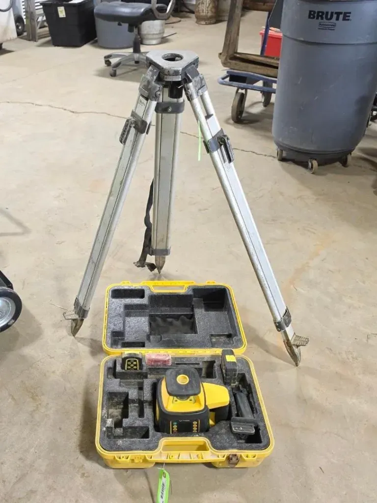 Tripod and yellow tool case on a concrete floor in a workshop/garage