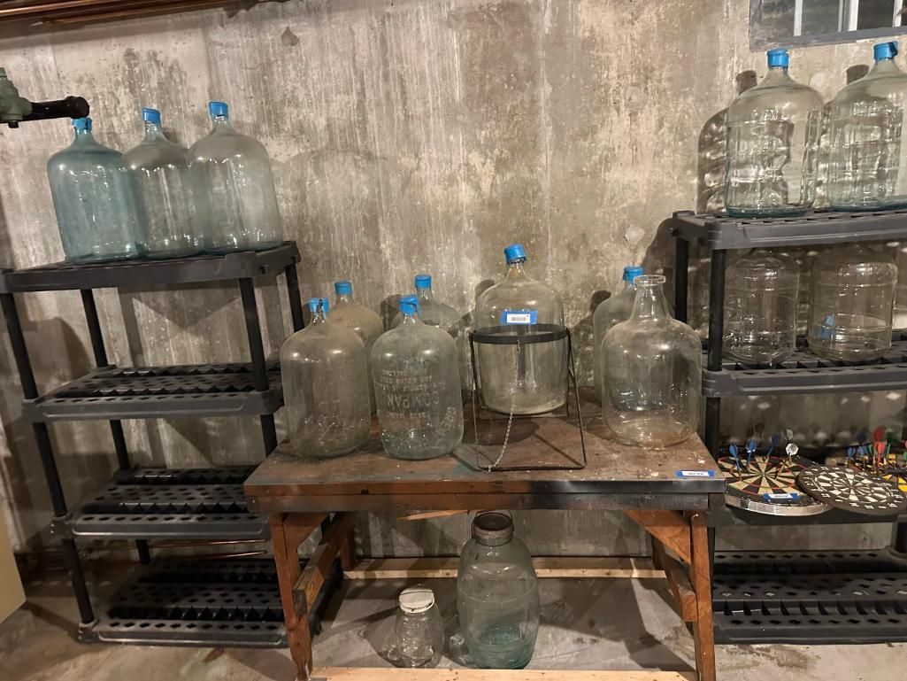 Glass water bottles with blue caps on shelves and a table.