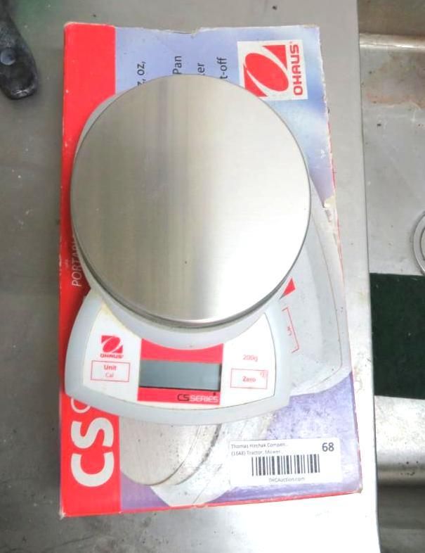 Silver and white Ohaus food scale on its box.