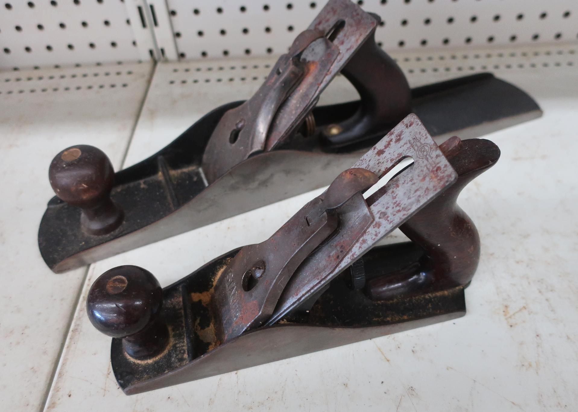 Two vintage wooden hand planes, metal blades, dark wood handles, on a shelf.