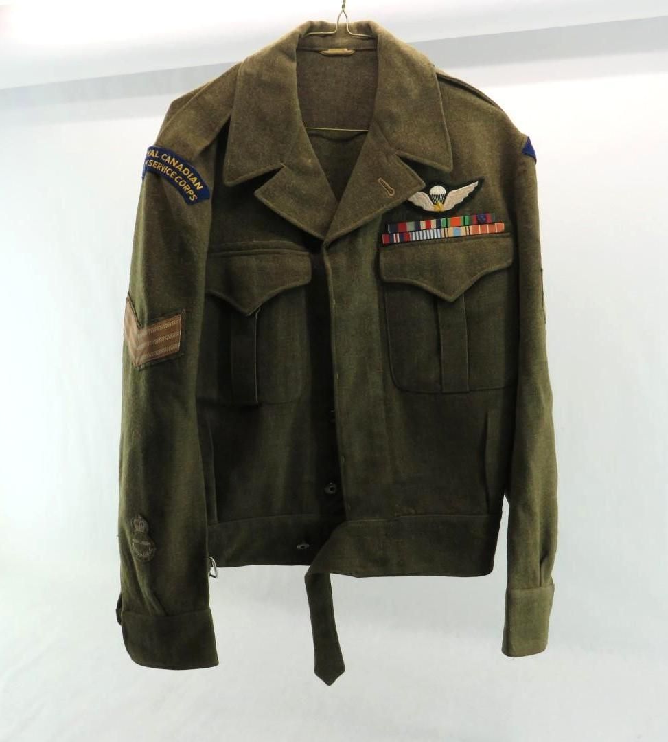 Olive-green military jacket with insignia and ribbons, hanging against a white background.