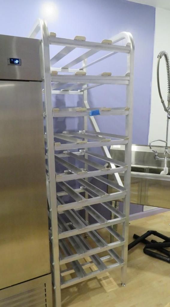 Tall, aluminum shelving unit next to a stainless steel refrigerator. Shelves are empty.