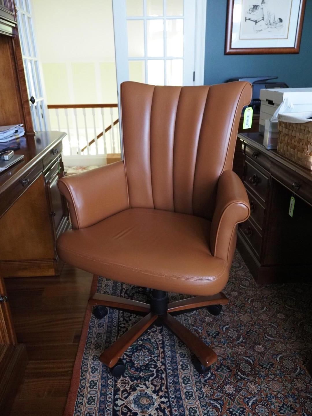 Brown leather office chair with high back, on a rug, near a desk.