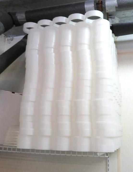 White plastic bottles stacked on a shelf. The bottles are cylindrical with wider bases and tops.