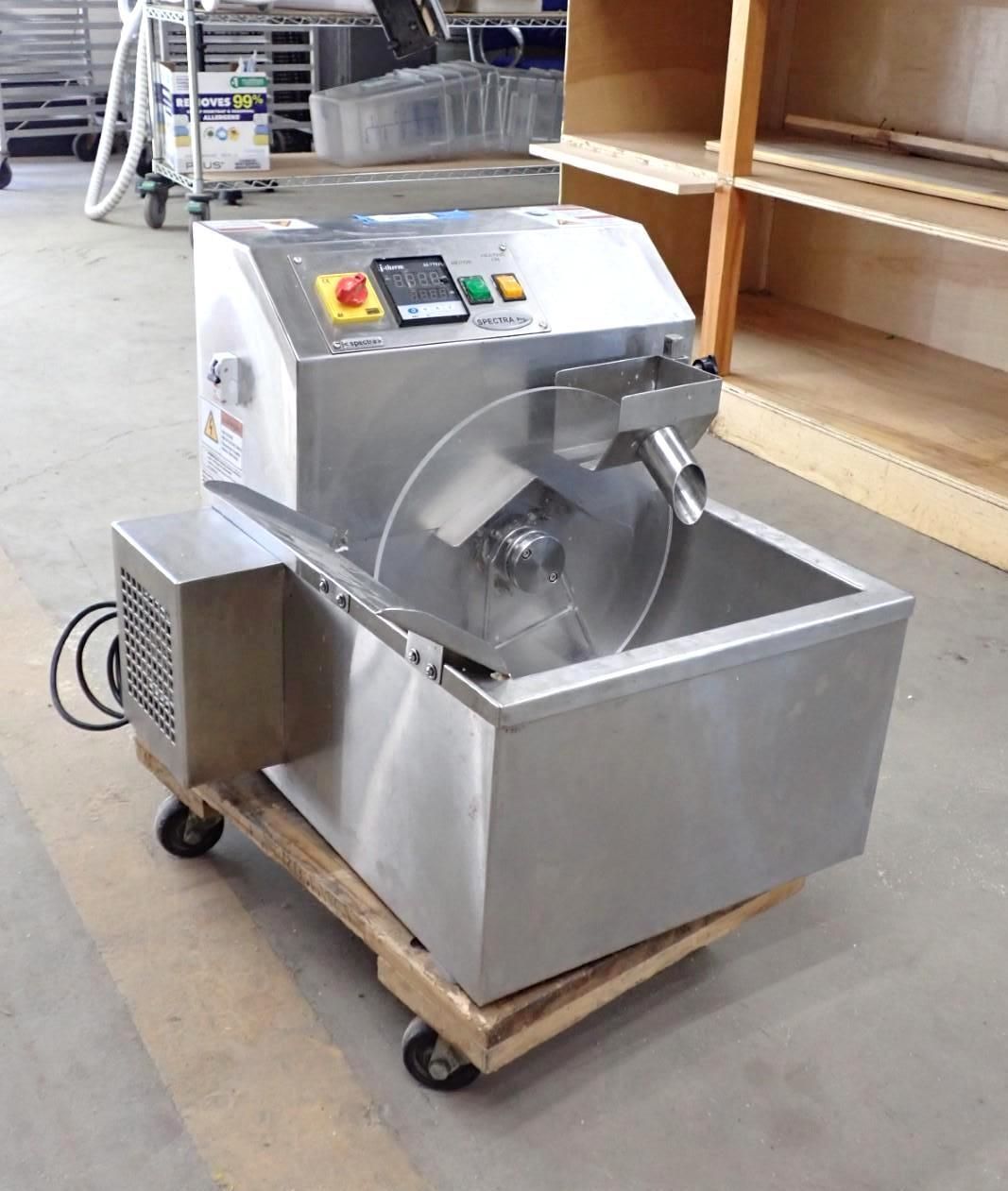 Stainless steel commercial food slicer on a pallet with wheels, indoors.