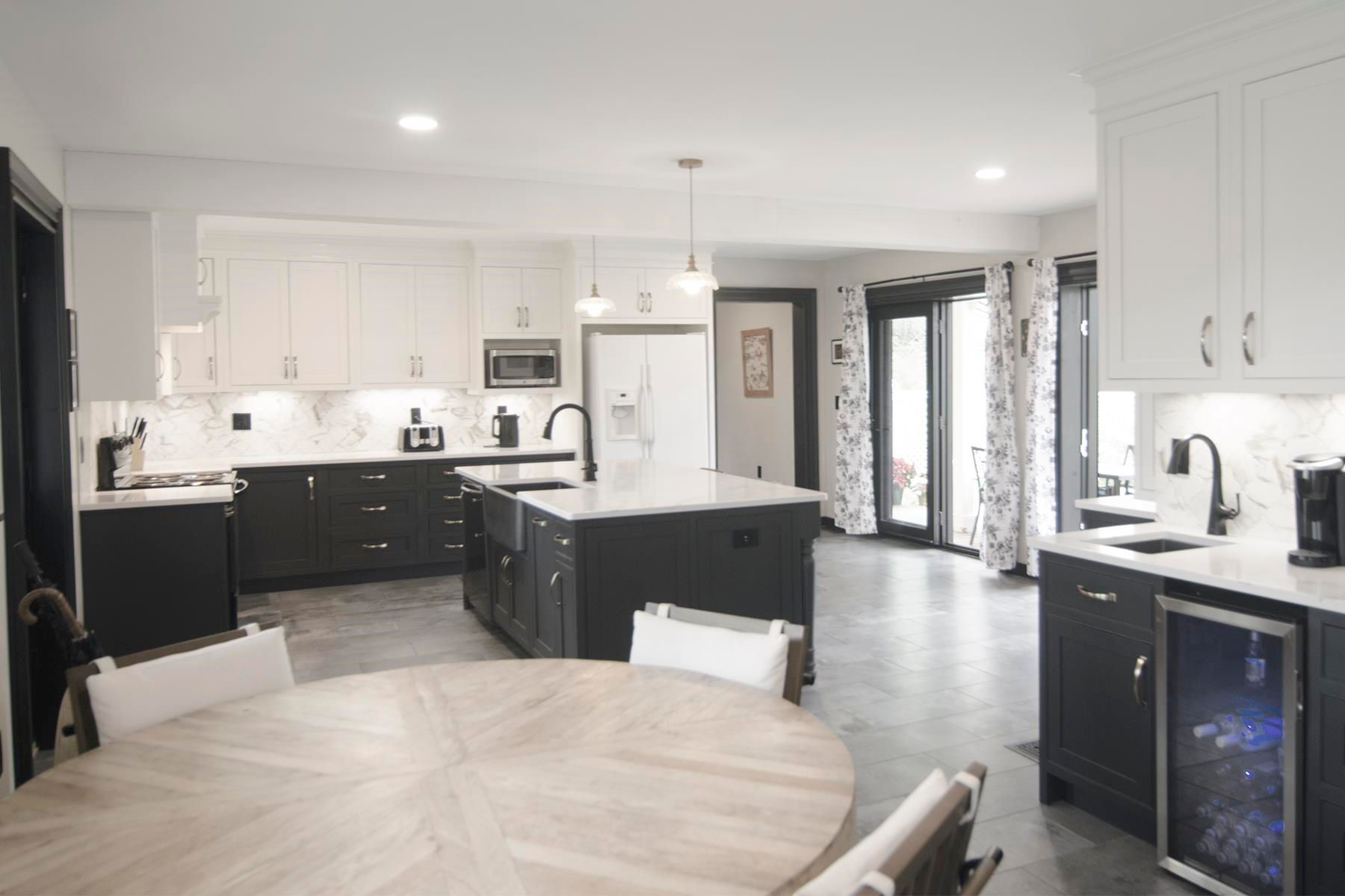 Modern kitchen with black and white cabinets, island, and round dining table.