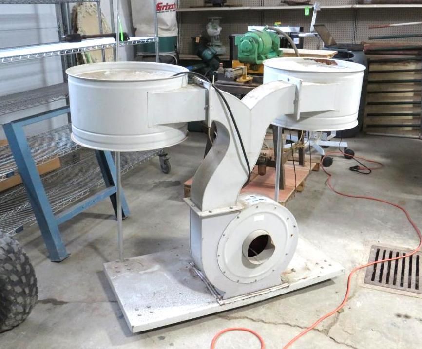 Large industrial blower system with dual intake, on a metal base, in a workshop.