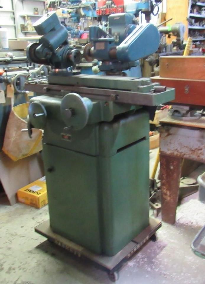 Green industrial grinding machine in a workshop setting.