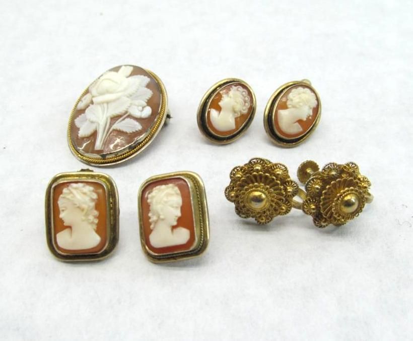 Set of cameo jewelry: brooch, two pairs of earrings, gold-toned frames, tan cameos, white carved figures.