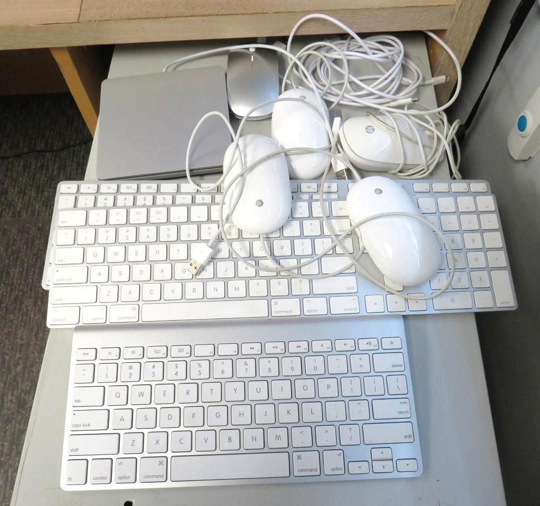 Two white keyboards and four white computer mice on a desk.