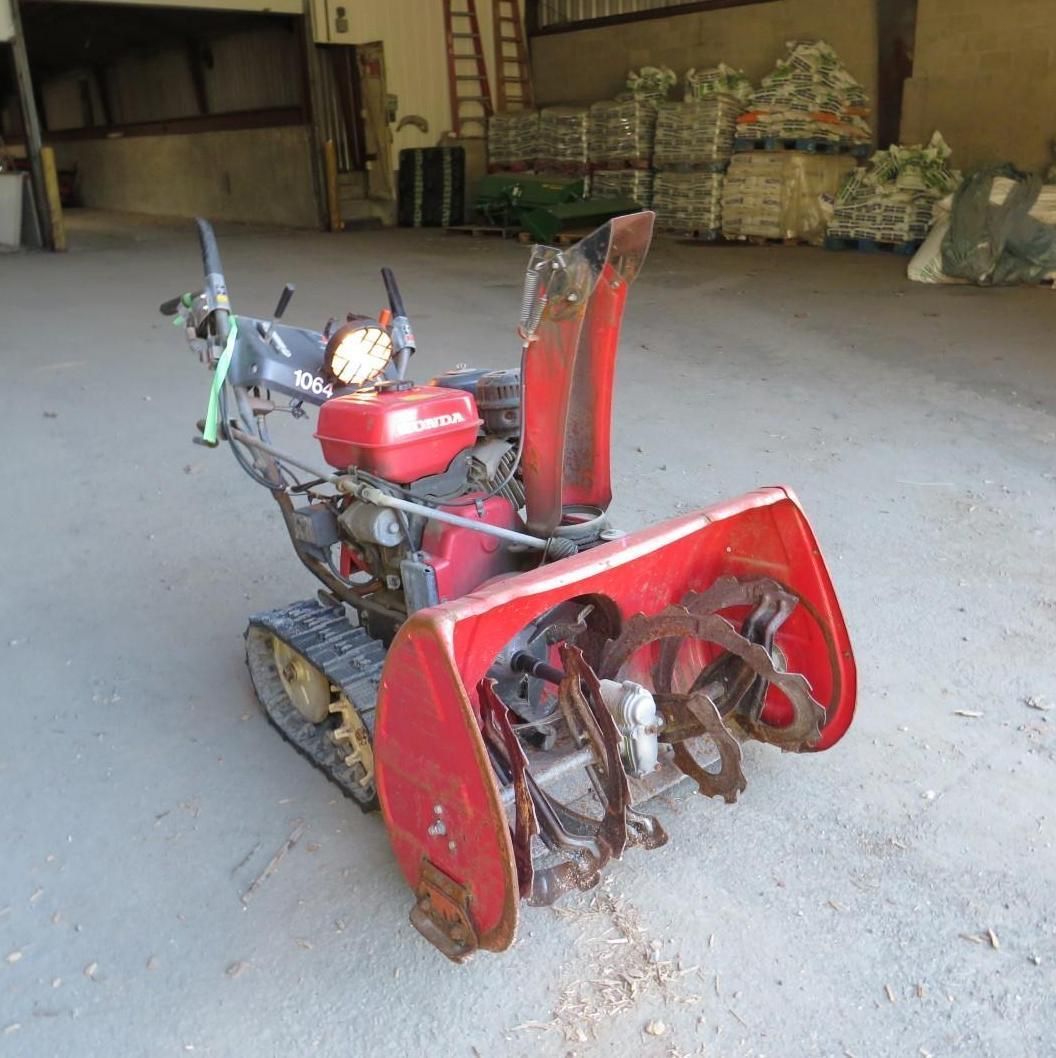 Red snow blower with tracks, in a warehouse.