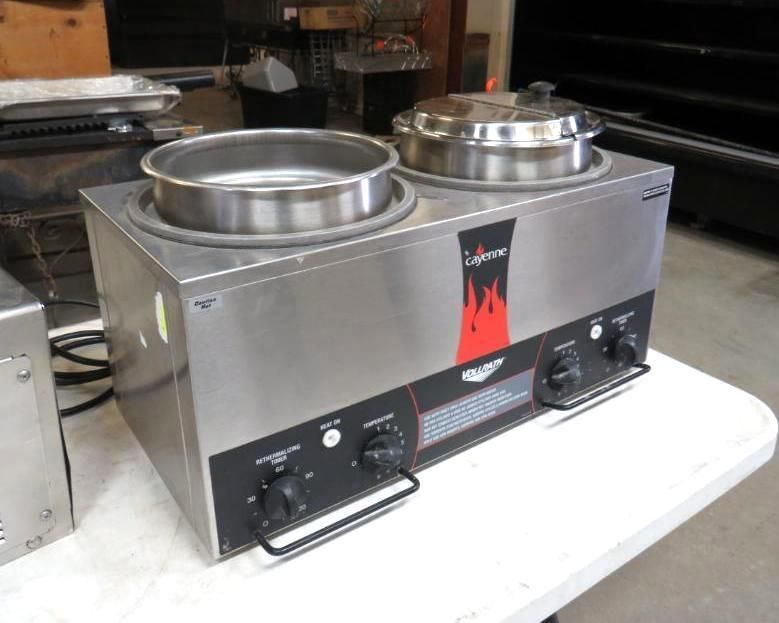 Stainless steel soup warmer with two pots, black control panel, on a white table.