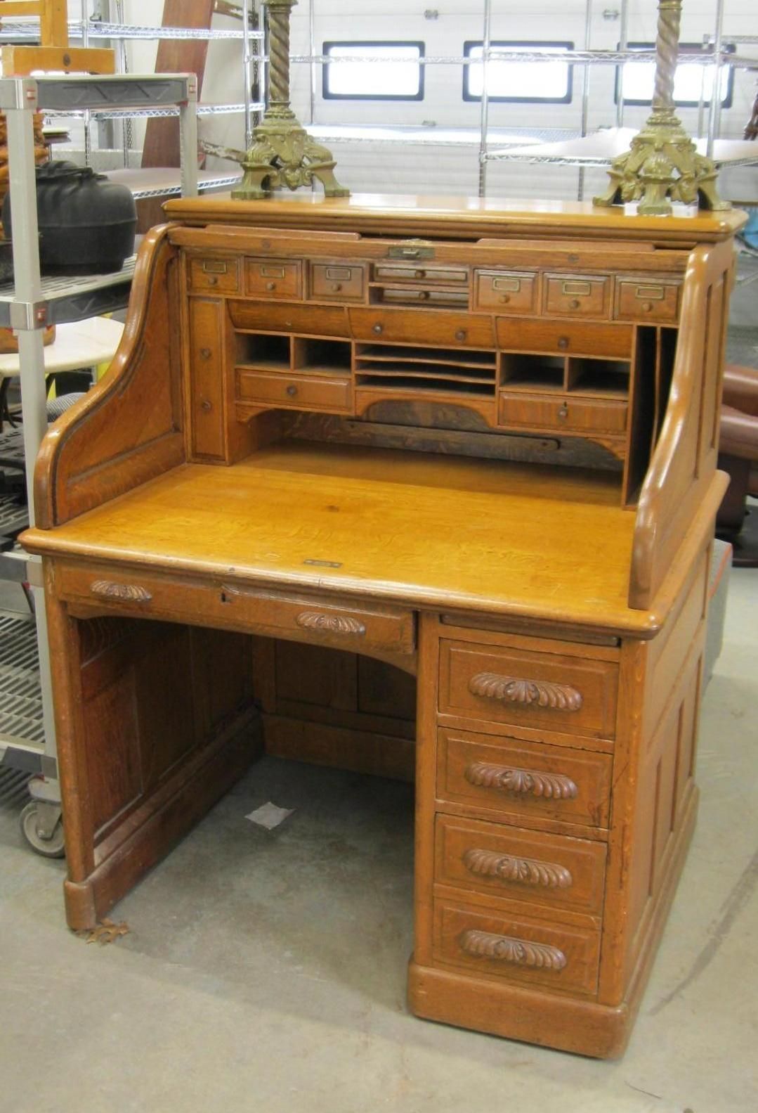 Wooden roll-top desk with multiple drawers and compartments.