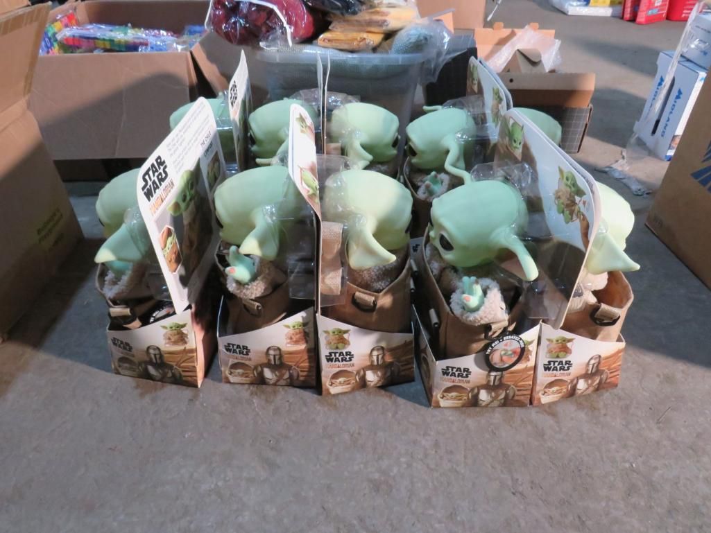 Group of Star Wars Grogu plush toys in their boxes, stacked on the floor.