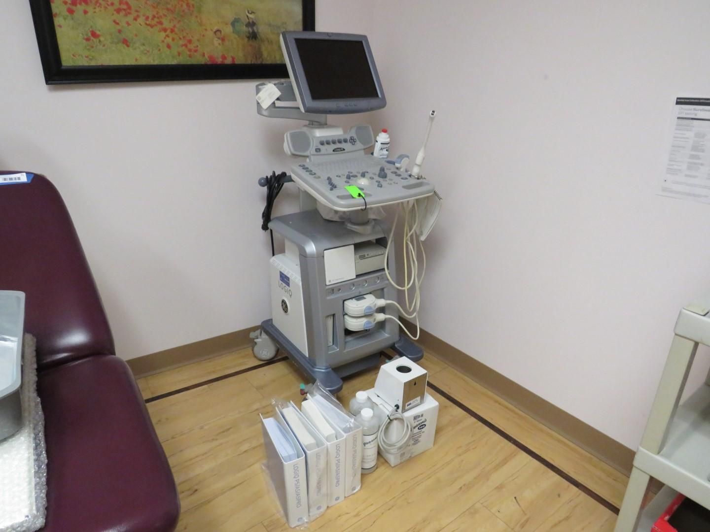 Ultrasound machine in a medical office, near a chair and wooden floor.