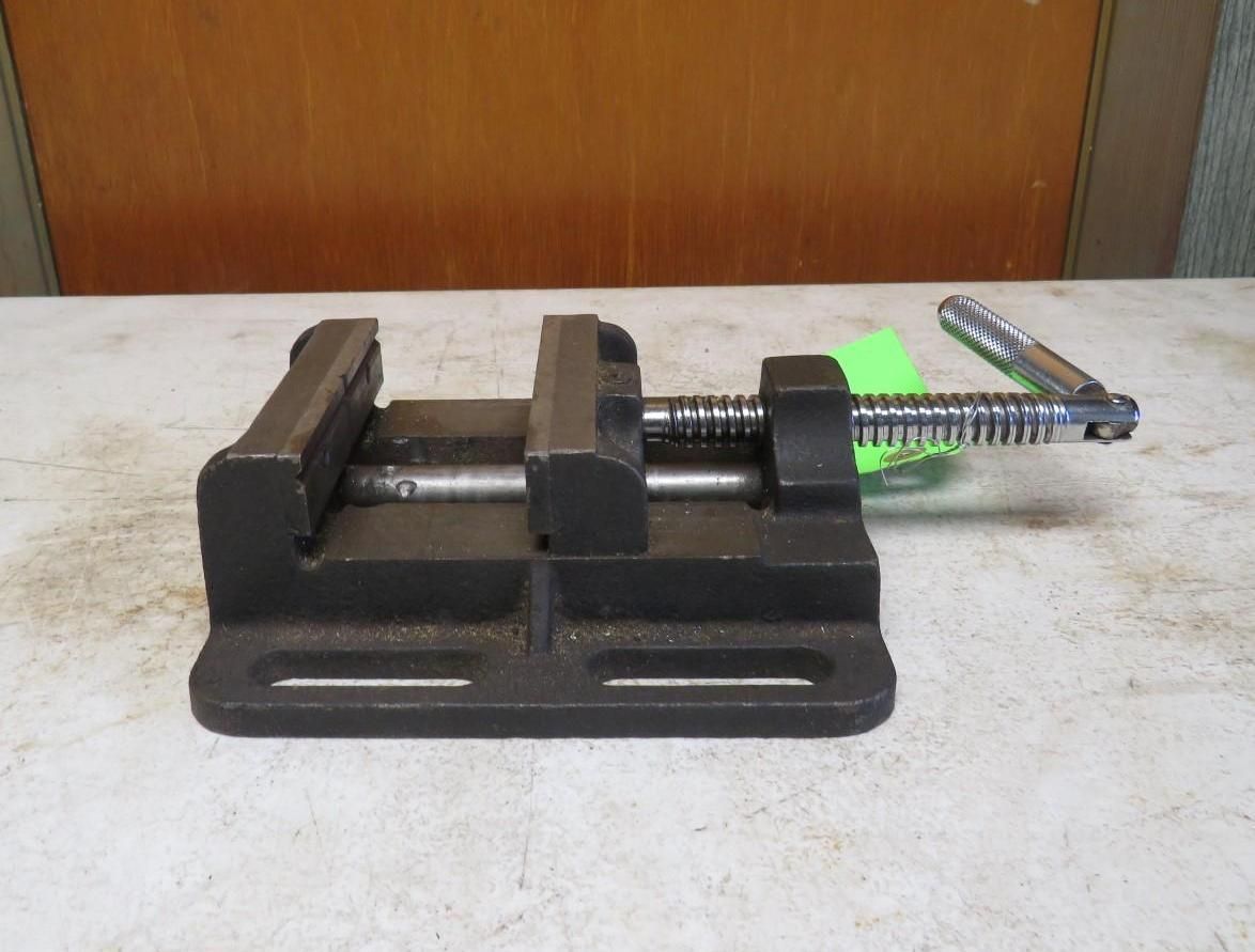 Black bench vise with a handle on a work surface.