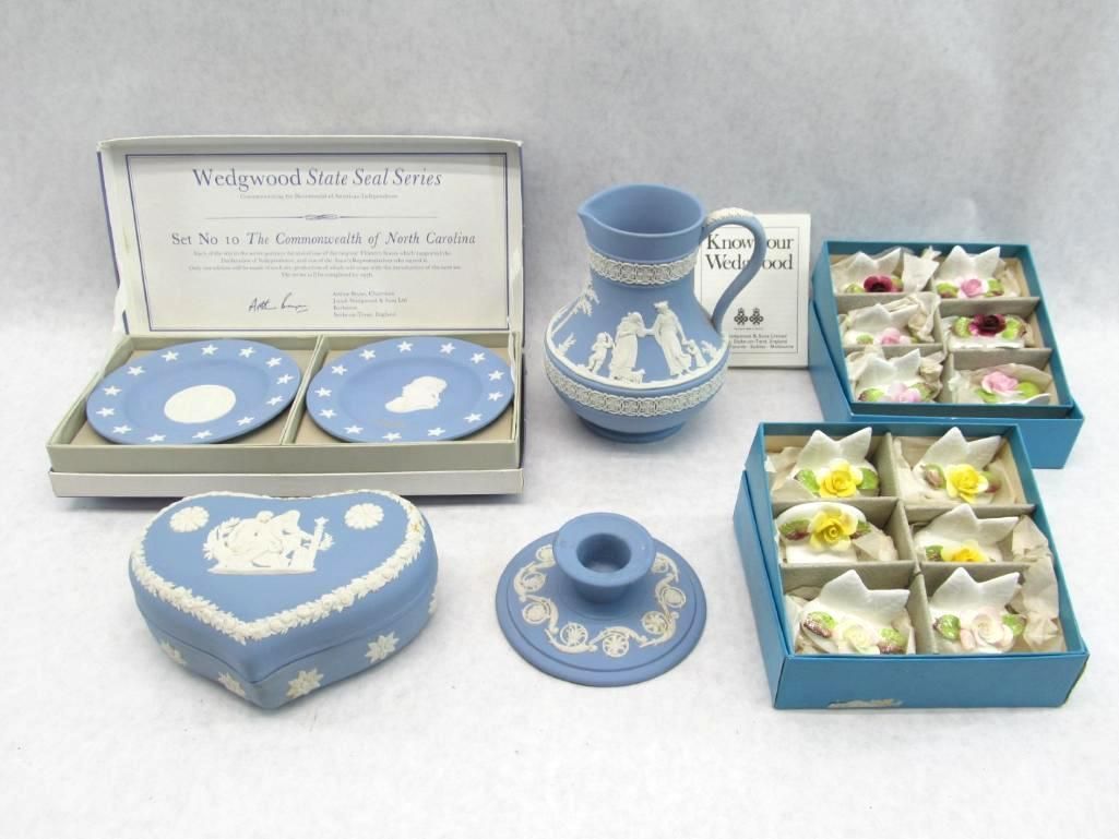 Collection of Wedgwood blue porcelain items in boxes: plates, pitcher, trinket box, candle holder, and floral accents.