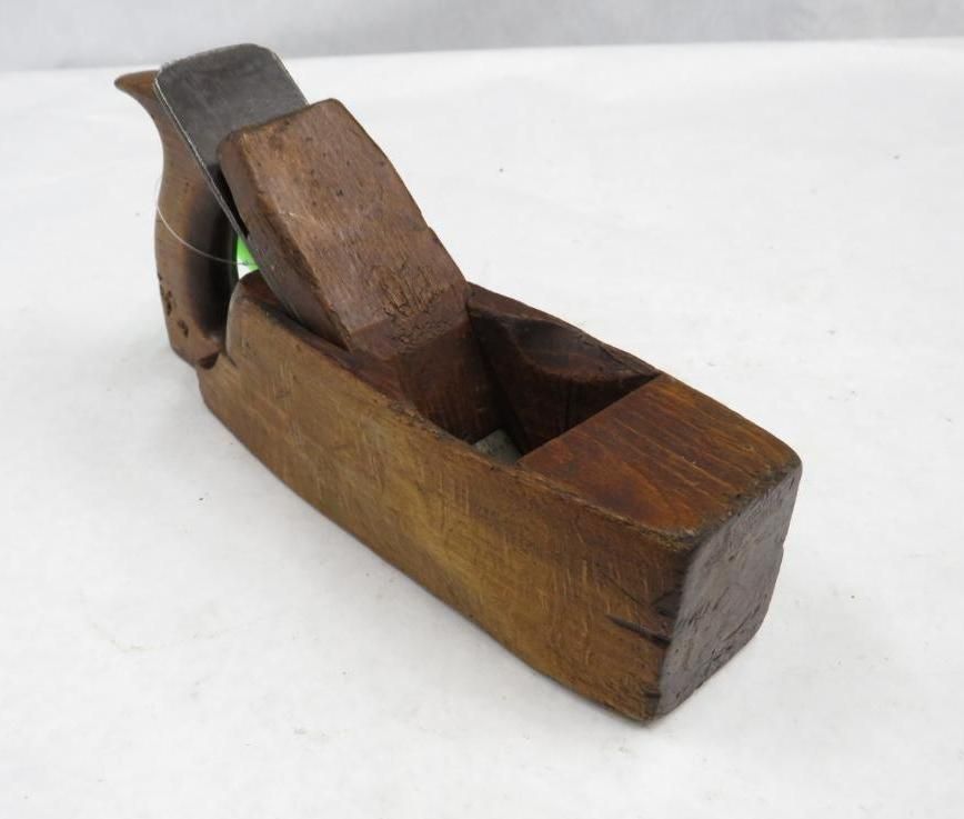 Wooden hand plane with a dark-colored body and blade, on a white surface.