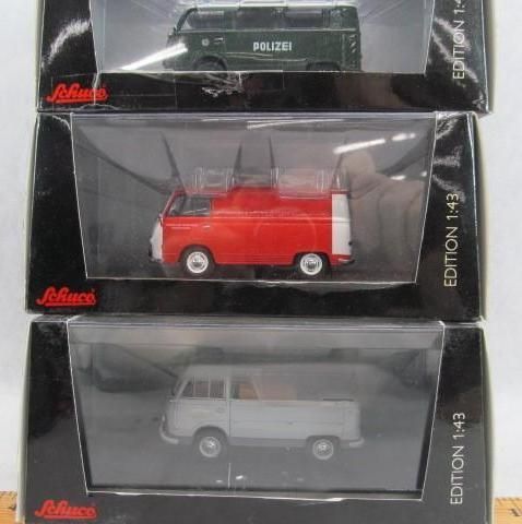 Three model Volkswagen vans in boxes: green police, red, and gray pickup.