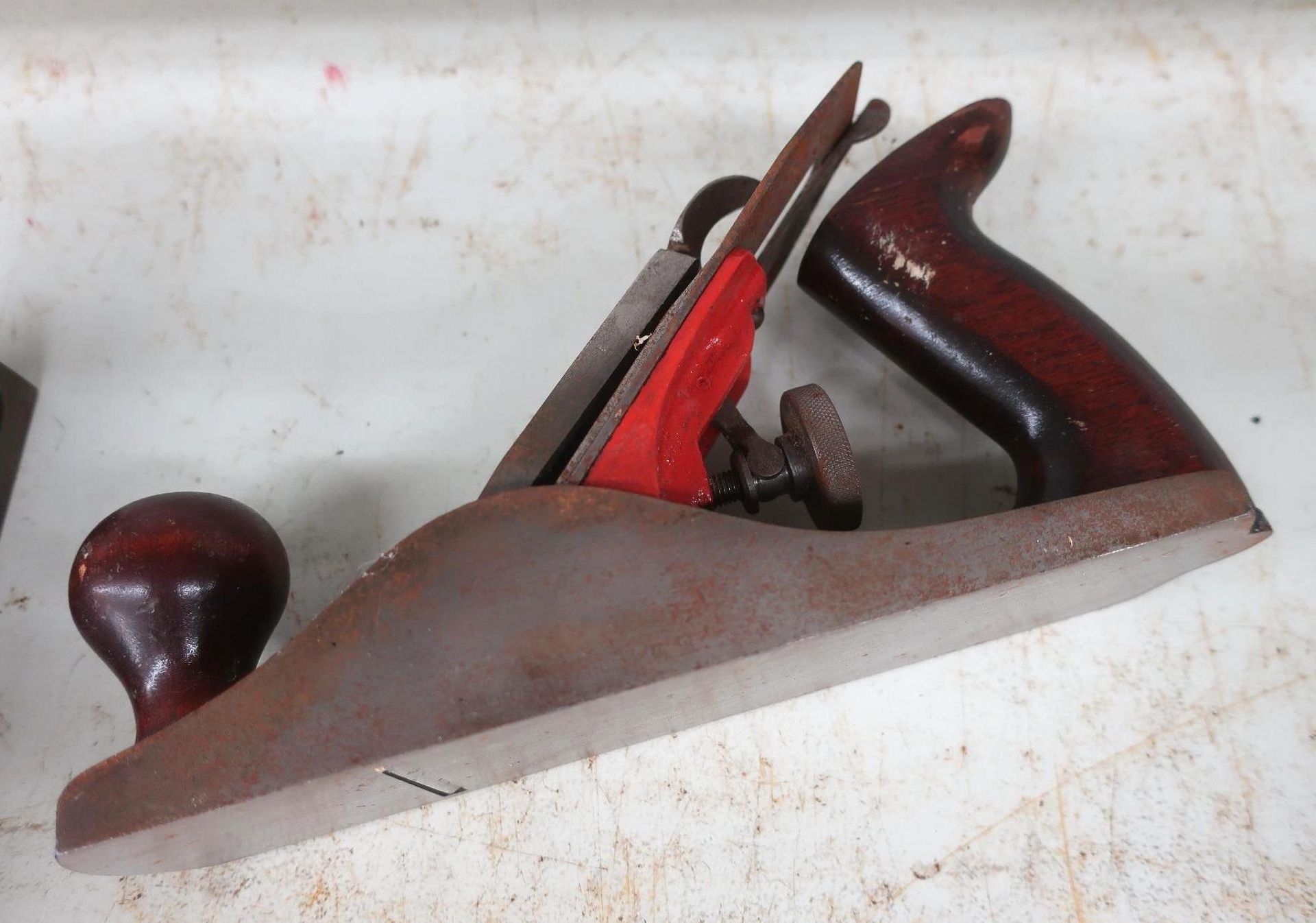 Hand plane tool with red and brown accents, resting on a white surface.