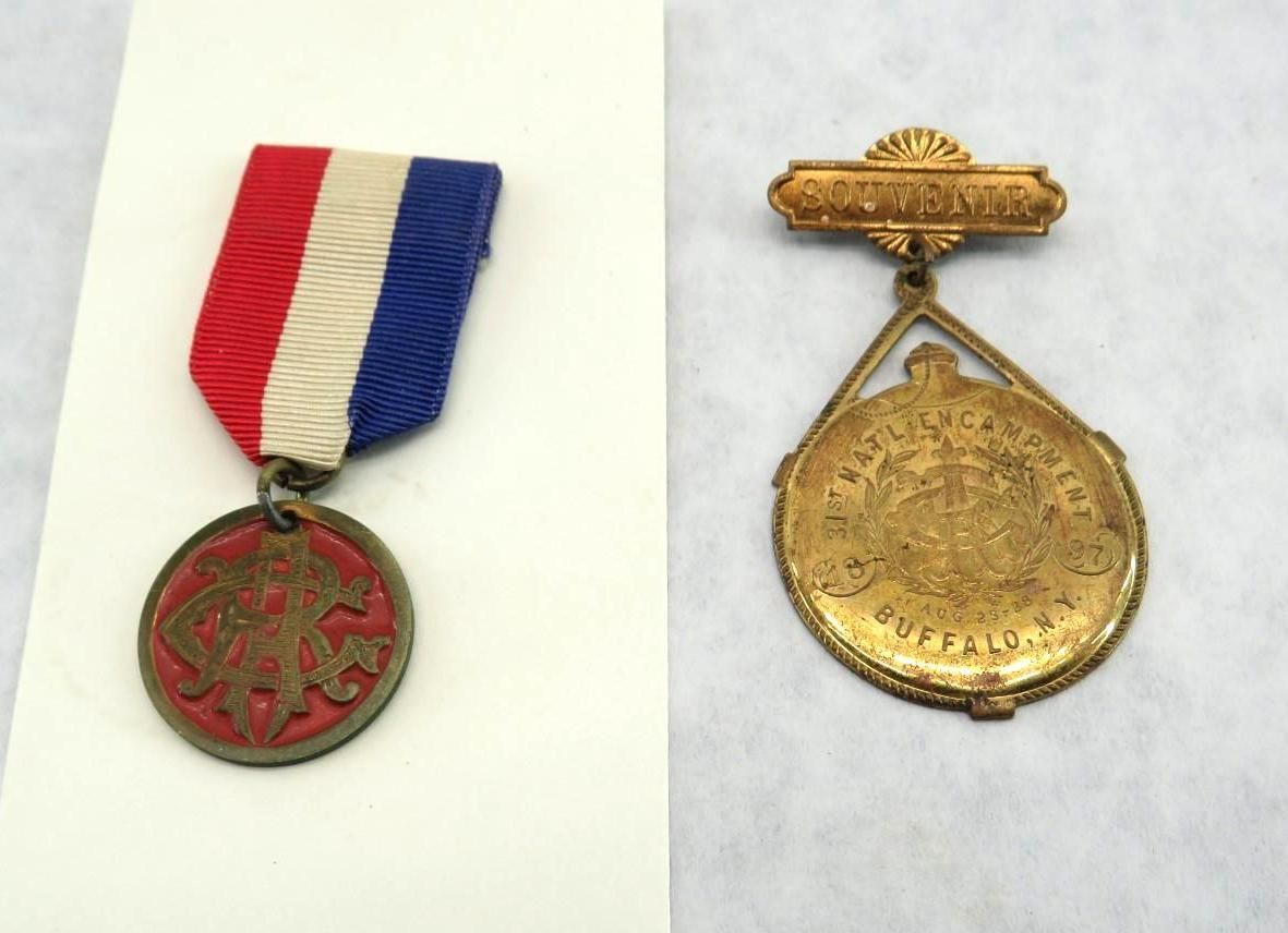 Two vintage medals: one with red, white, and blue ribbon; the other gold, with text and ornate design.
