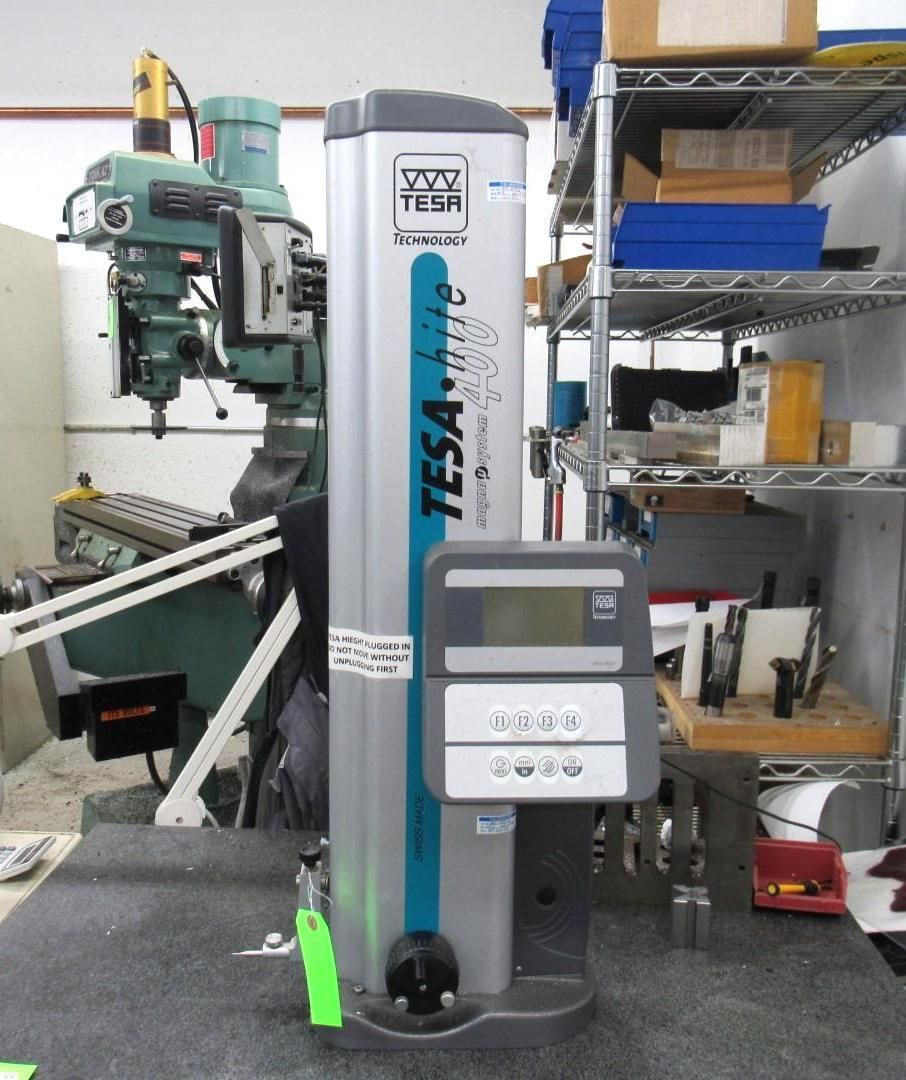 A silver TESA-hite measuring device with a digital display, in a workshop setting.
