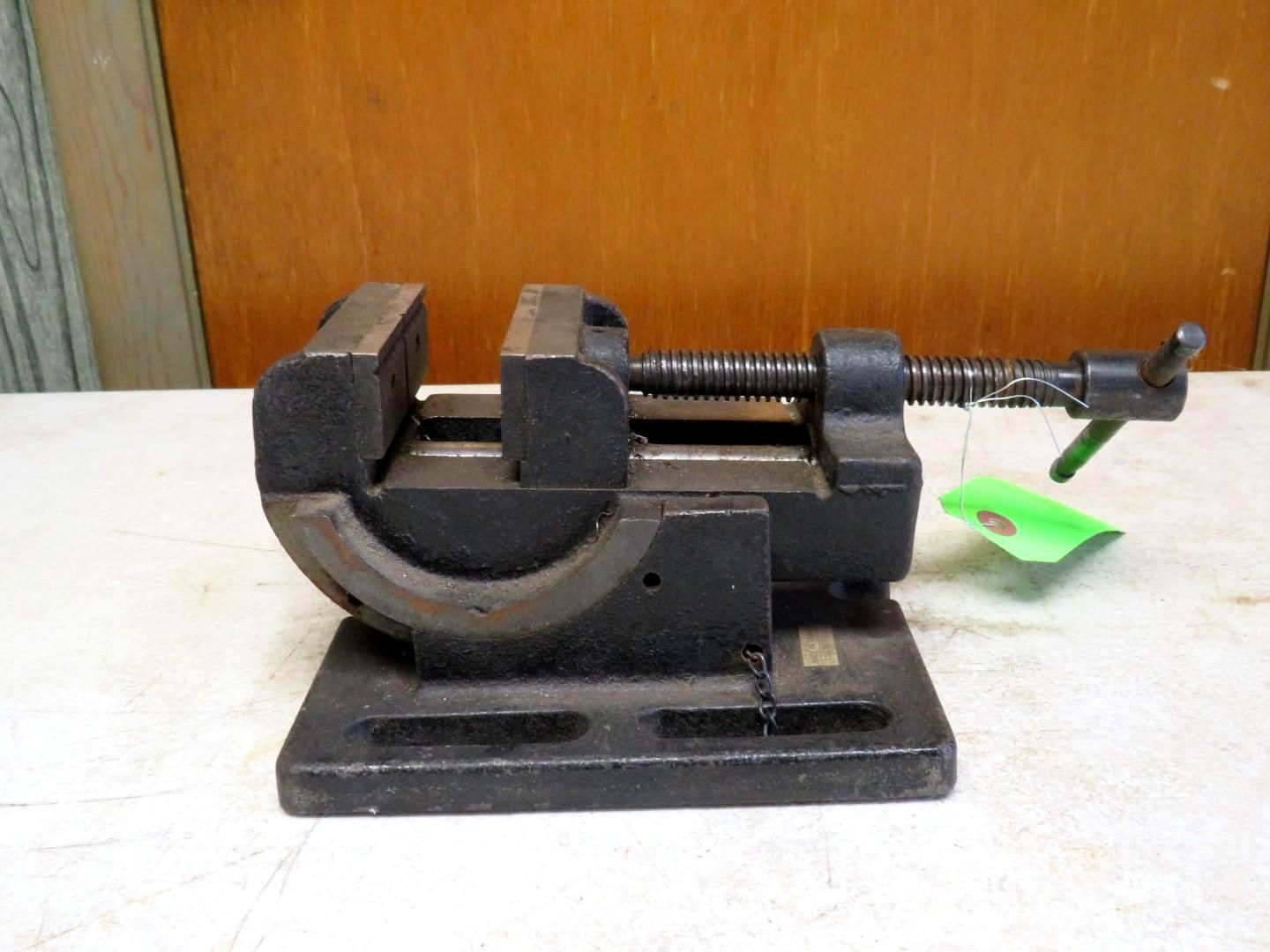 Black metal swivel vise on a workbench.