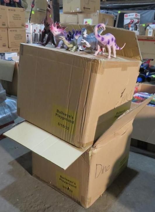 Cardboard boxes stacked, one open. Dinosaur toys sit on top.
