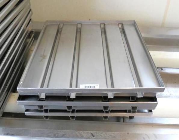 Stainless steel food trays stacked on a shelf.