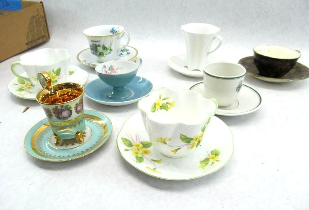Assortment of teacups and saucers on a white surface, featuring floral designs and various colors.