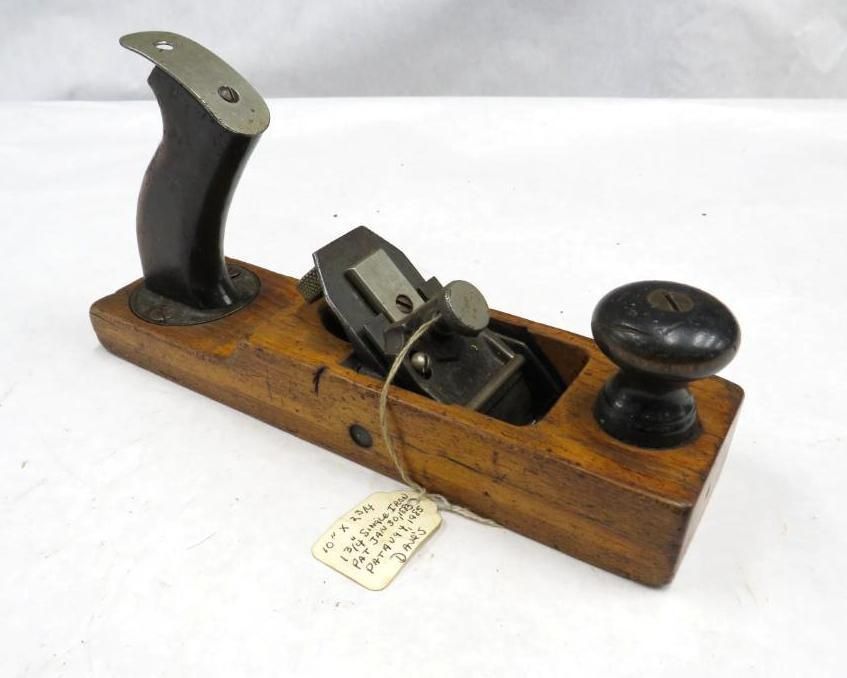 Wooden hand plane with a dark handle and knob, metal blade, and a tag.