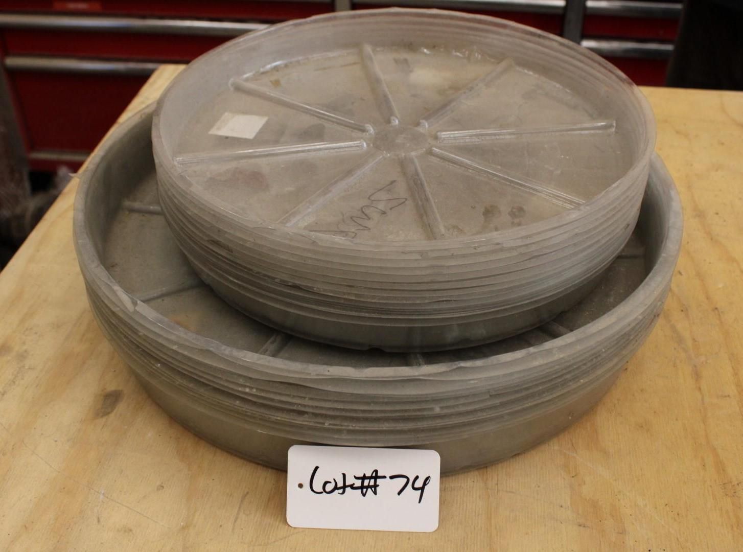 Stack of gray plastic plant saucers. Labeled