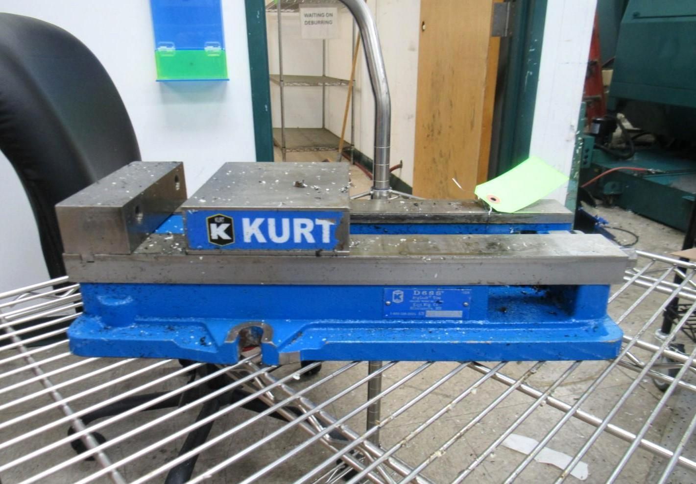 Blue Kurt vise sitting on a metal rack in a workshop setting.