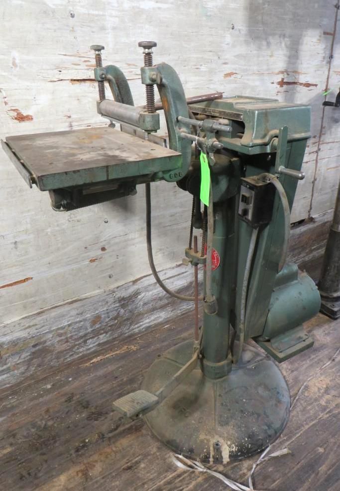 Green industrial paper cutter machine in a workshop.