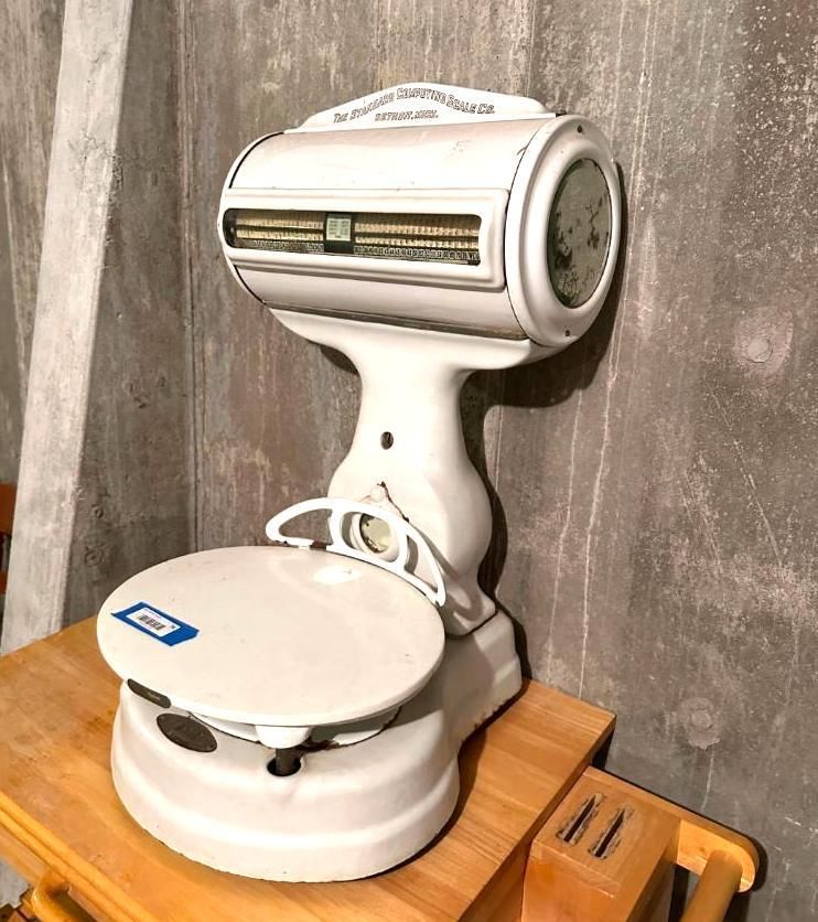 White antique weighing scale on a wooden table.