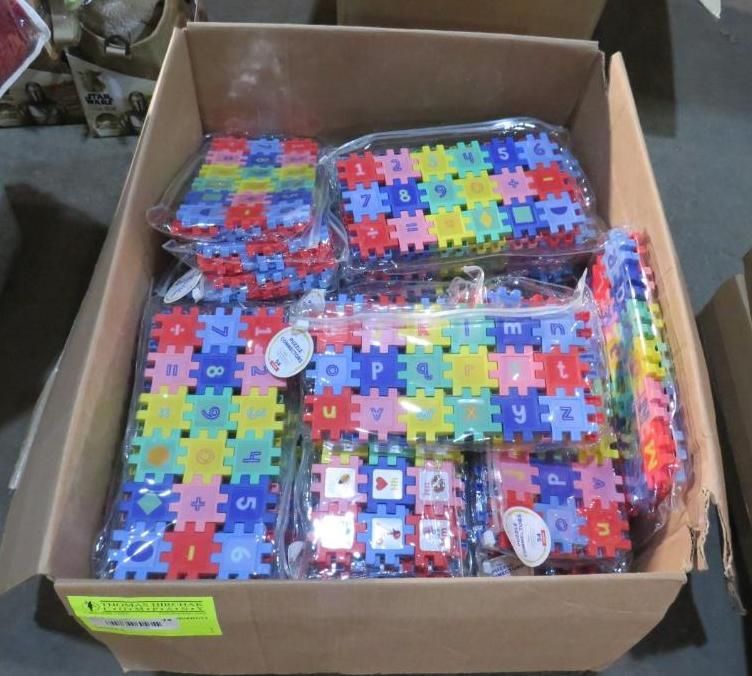 Cardboard box filled with packaged alphabet puzzle pieces in various colors.